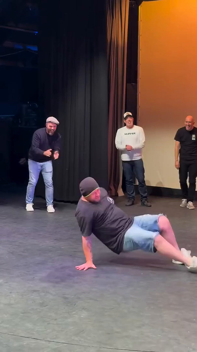 A dad pulling a floor move while the other dads cheer him on