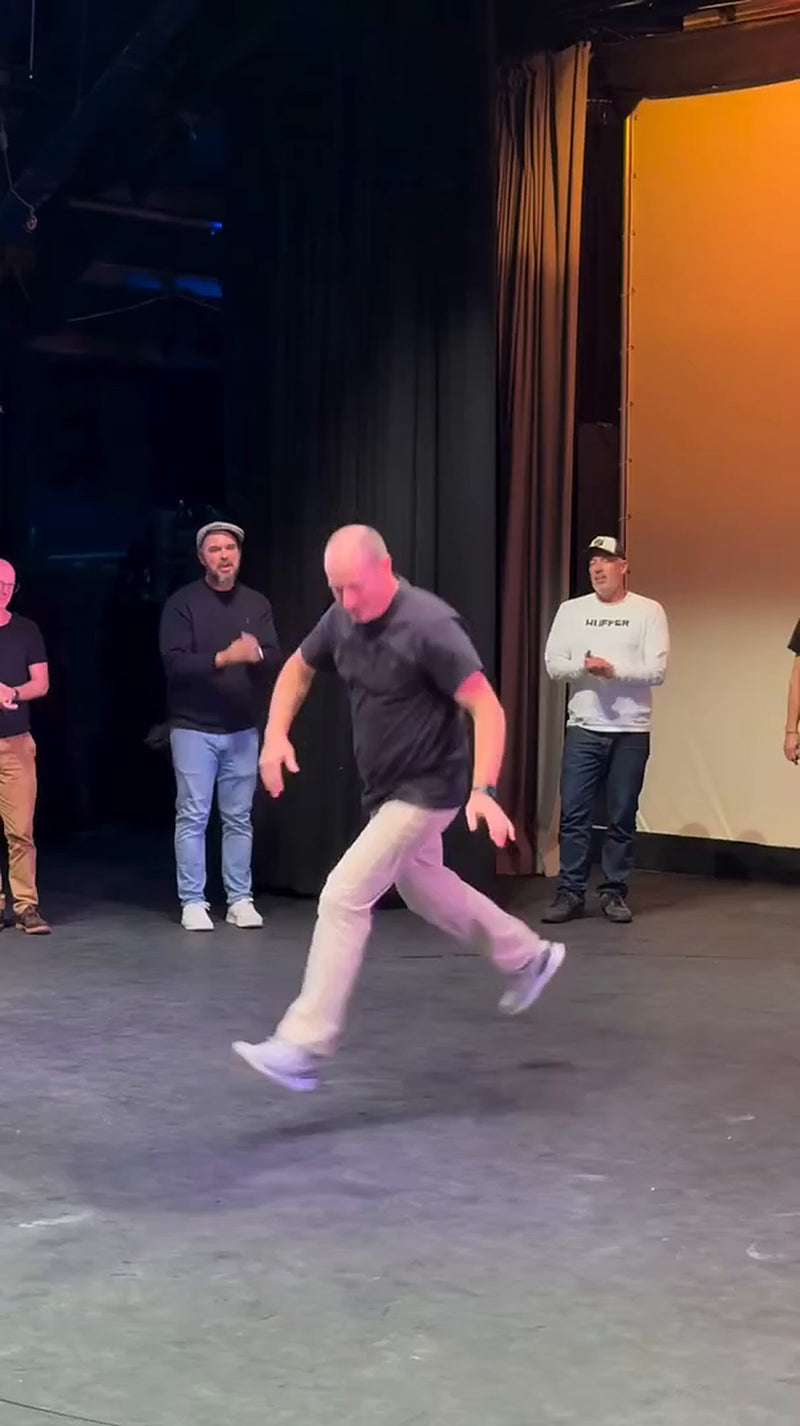 A dad in a full-stretch lunge on stage at the Dance Dad Battle