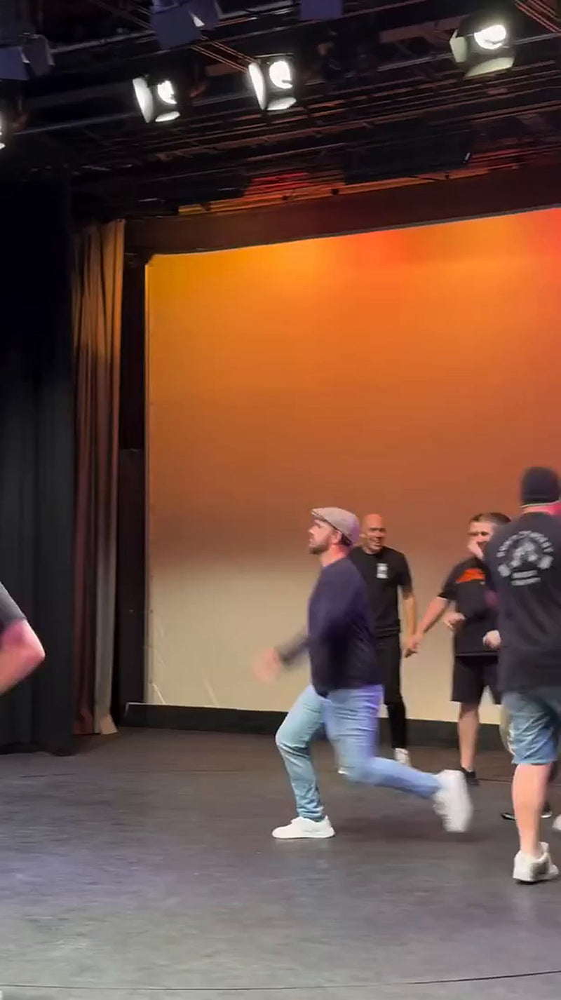 Dads on stage under the lights at the Dance Dad Battle
